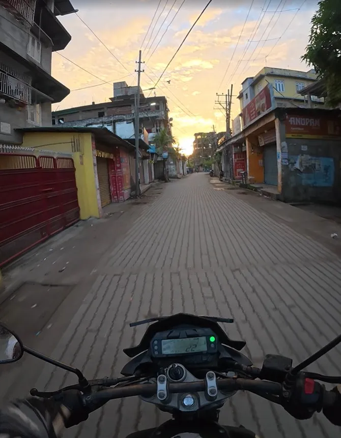 Rider's view from our Yamaha FZ rental bike on a quiet town street under a golden sky
