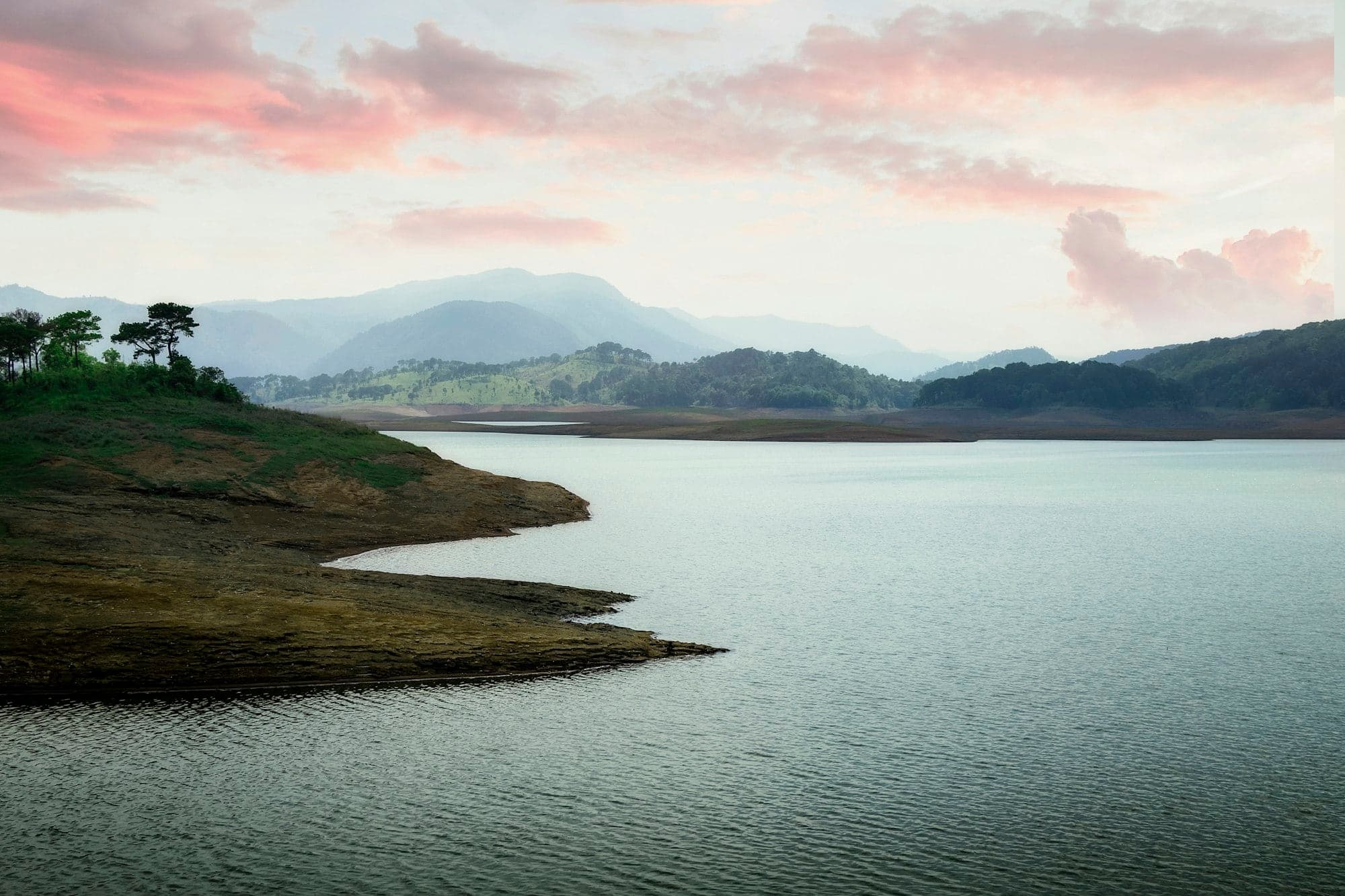 Umiam Lake at sunset with pink clouds and pine-covered hills, Meghalaya
